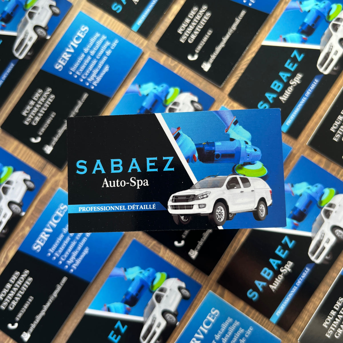 Collection of Sabaez business cards with car illustrations on a wooden surface.
