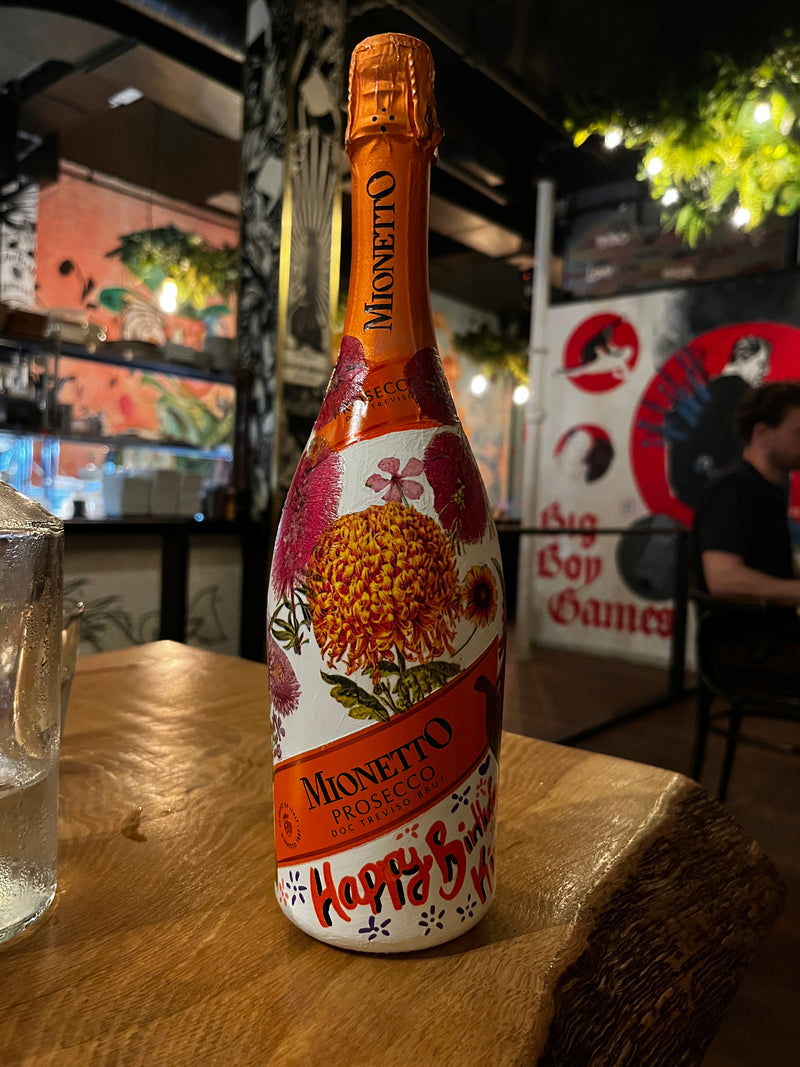 Bottle of Mionetto Prosecco on a wooden surface with a blurred background
