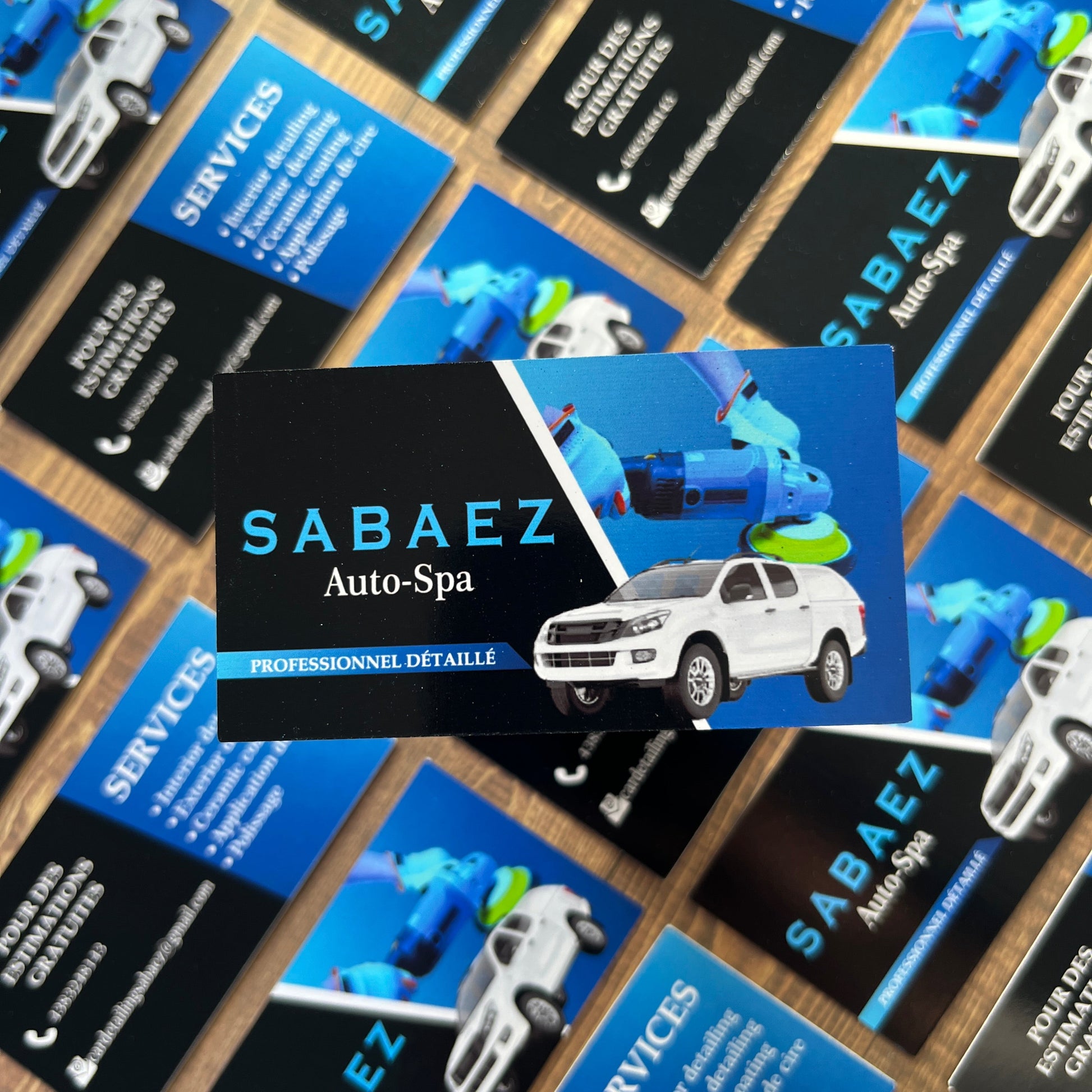 Collection of Sabaez business cards with car illustrations on a wooden surface.