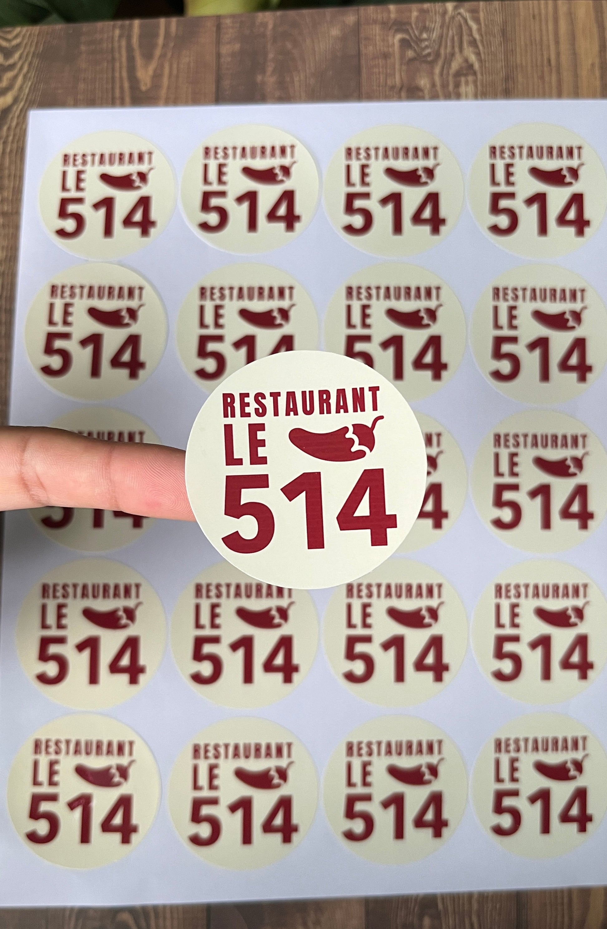 Sheet of 'Restaurant Le 514' stickers with a hand holding one sticker.