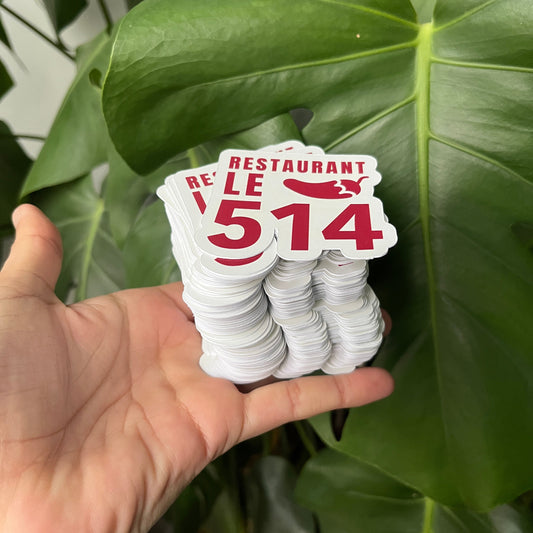 Hand holding a white card with red text against a green leafy background