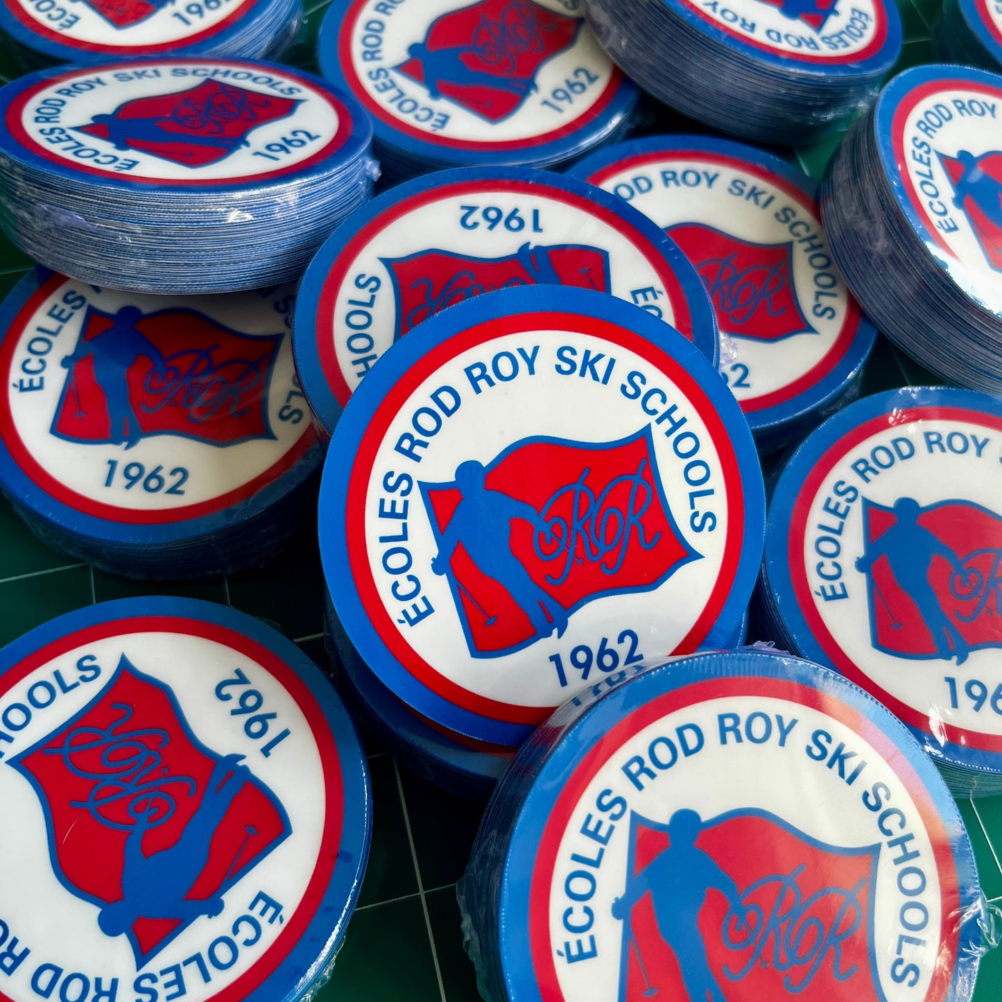 Collection of Écoles Rod Roy Ski Schools branded stickers on a green cutting mat.
