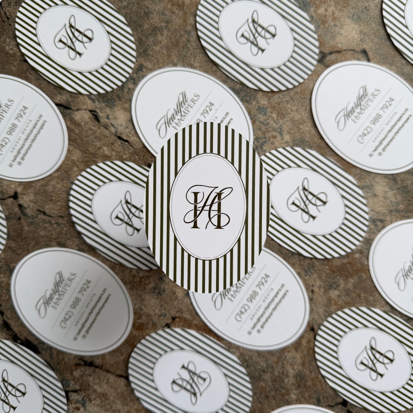 Collection of oval labels with monogram and text on a textured surface