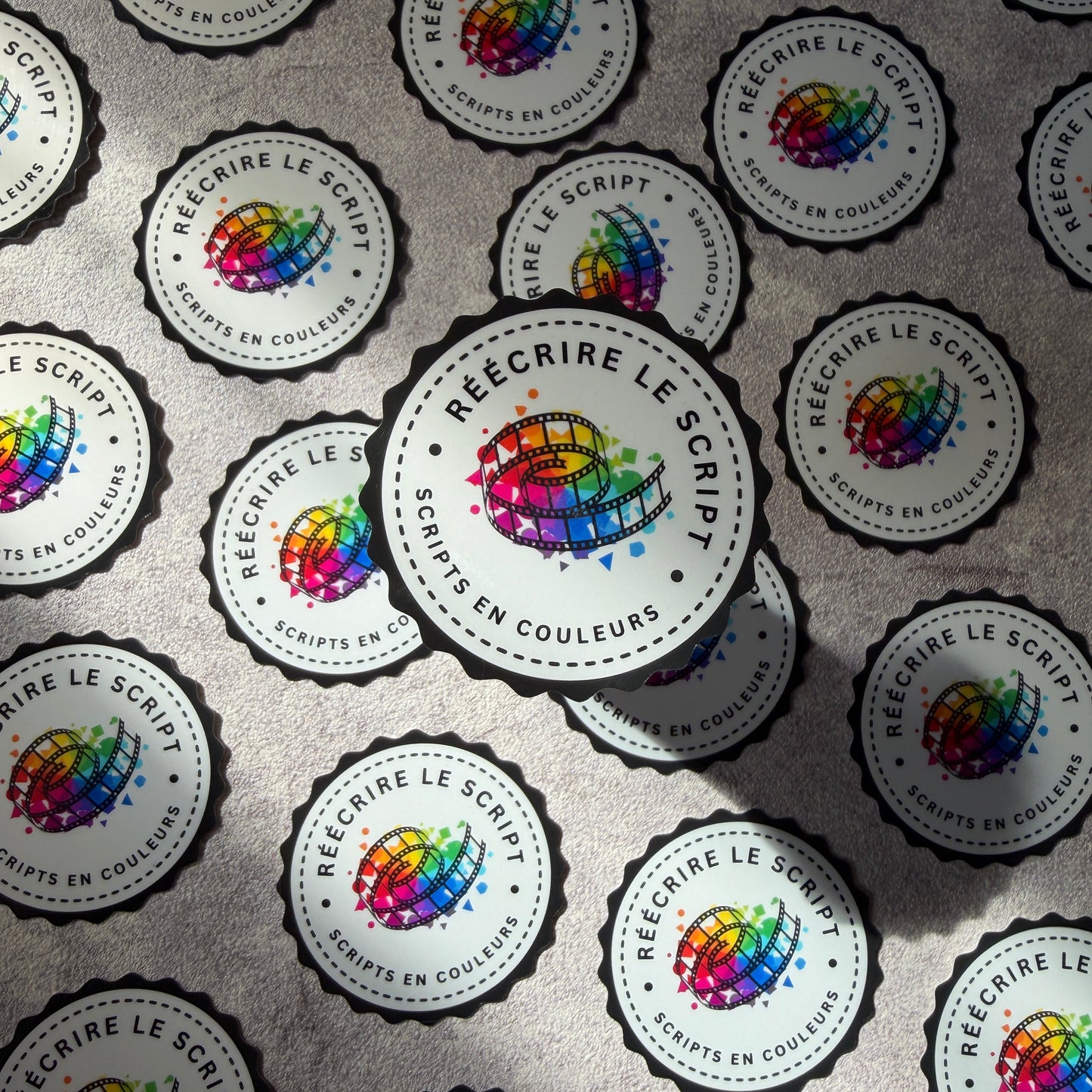 Pattern of round stickers with colorful logos and text on a gray background