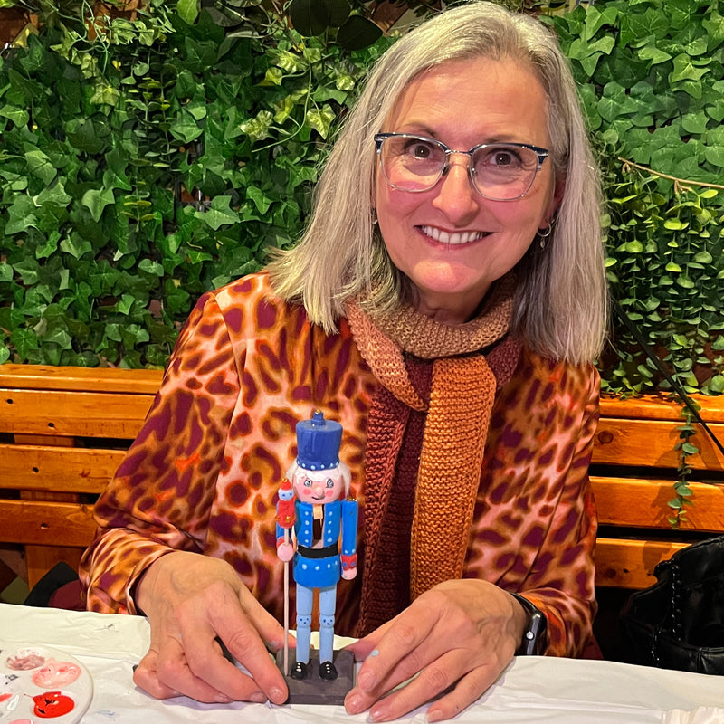 Woman holding a nutcracker with greenery in the background